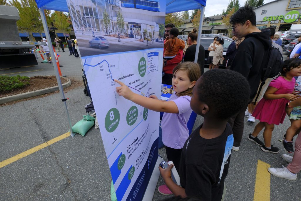 Two children inspect a map of the future Surrey Langley SkyTrain route.