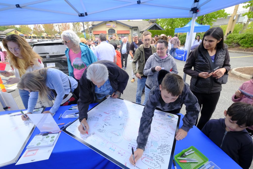 A crowd gathers around the segment boards to sign them.